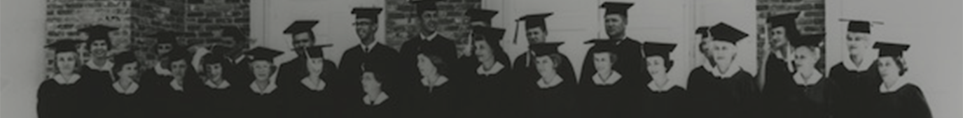 Black and white photo of about 20 people standing in cap and gown