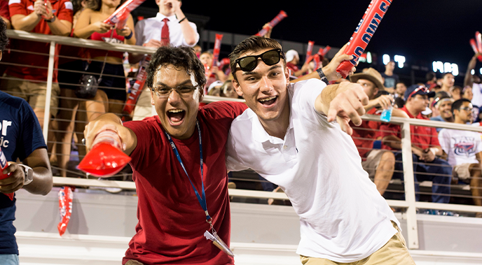 Two male students during an 妖爱直播 football game smiling and pointing at the camera